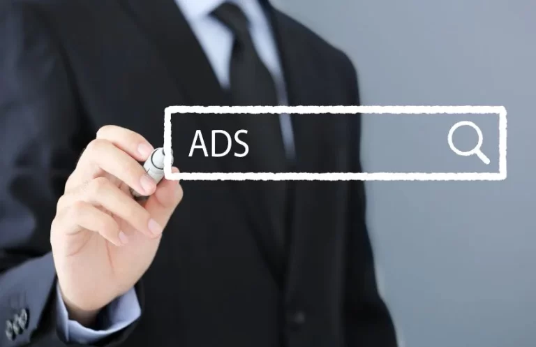 Un ejecutivo con traje dibujando una barra de búsqueda con el texto “ADS” y un icono de lupa sobre fondo neutro, representando campañas en Meta Ads
