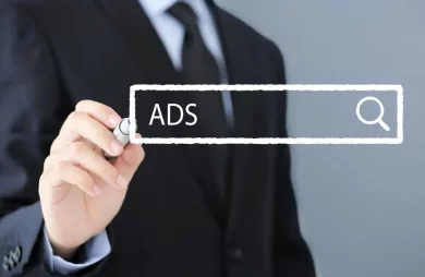 Un ejecutivo con traje dibujando una barra de búsqueda con el texto “ADS” y un icono de lupa sobre fondo neutro, representando campañas en Meta Ads