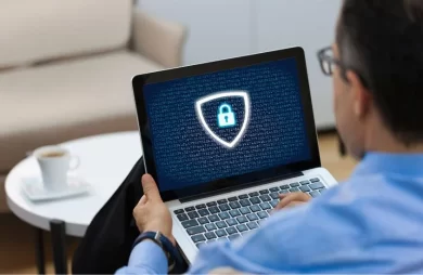 Hombre consultando en su portátil cómo adaptar su web al RGPD, con un icono de ciberseguridad en pantalla que simboliza la protección de datos.