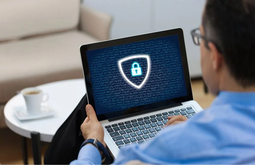Hombre consultando en su portátil cómo adaptar su web al RGPD, con un icono de ciberseguridad en pantalla que simboliza la protección de datos.
